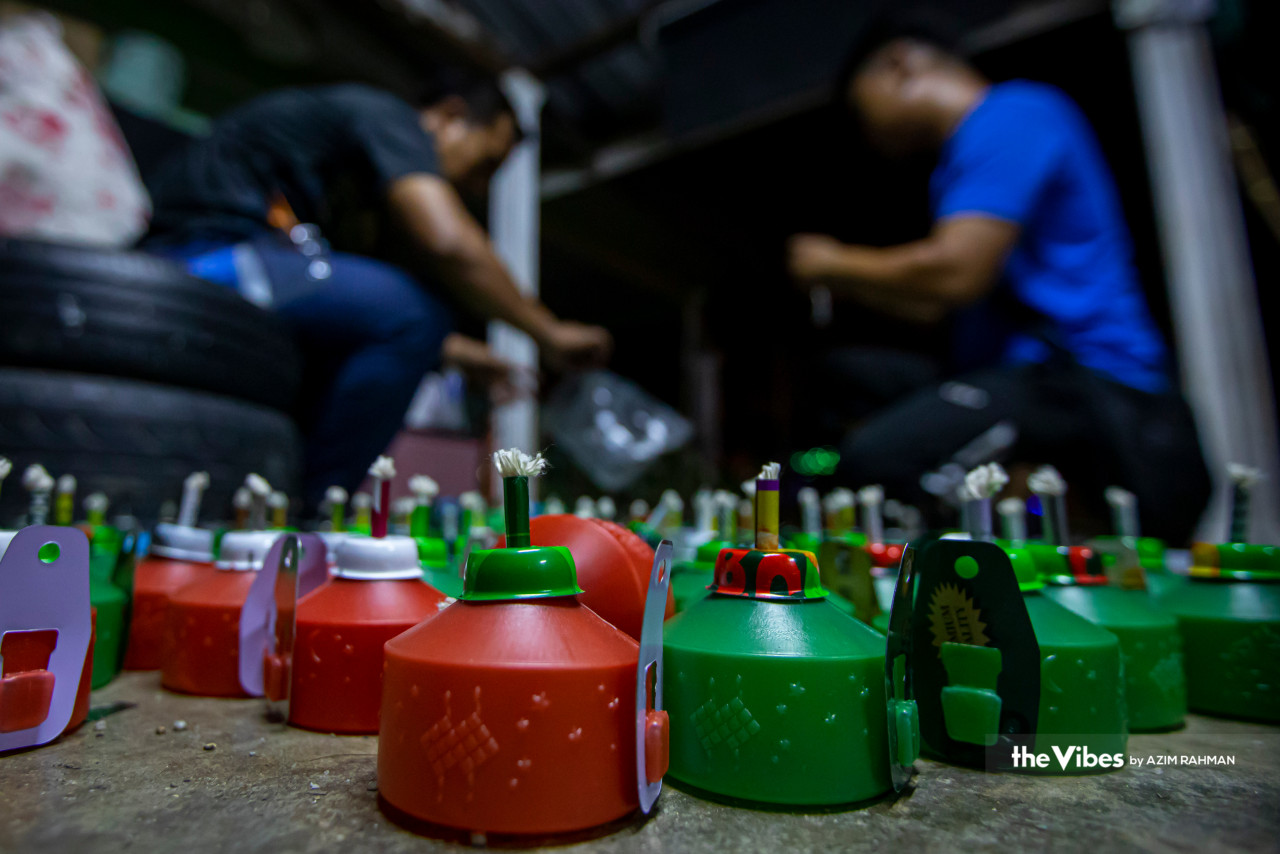 Beberapa remaja memasang pelita, iaitu antara tradisi pada malam raya.