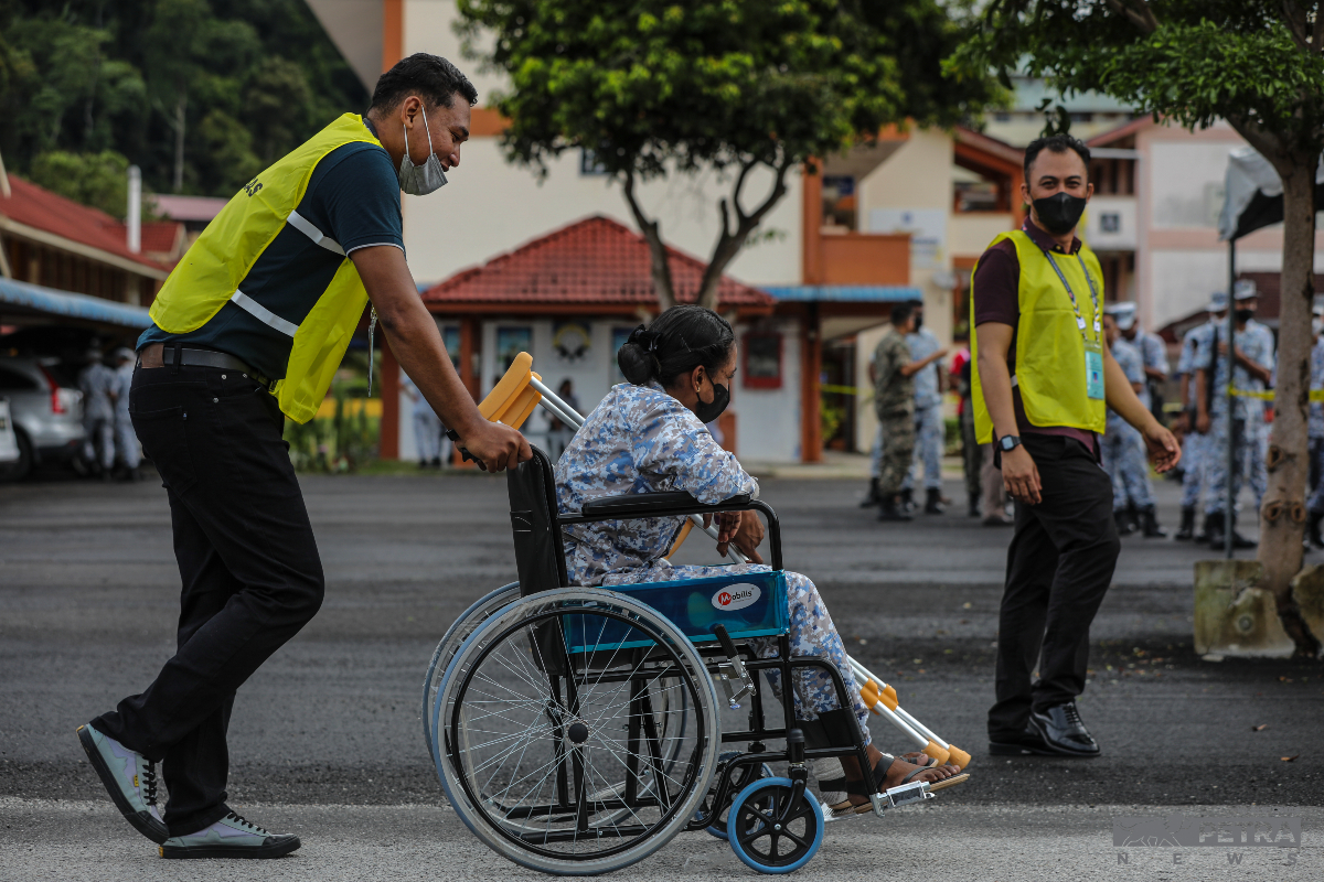 Petugas SPR membantu seorang anggota TLDM mengundi SMK Pangkalan TLDM Lumut. 