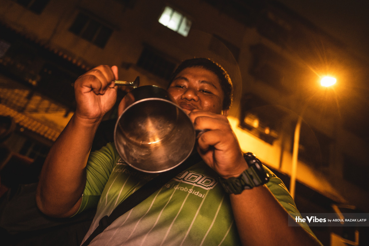 Gelagat lucu seorang penduduk yang menggunakan kole minuman sebagai gendang bagi mengeluarkan bunyi-bunyian. 
