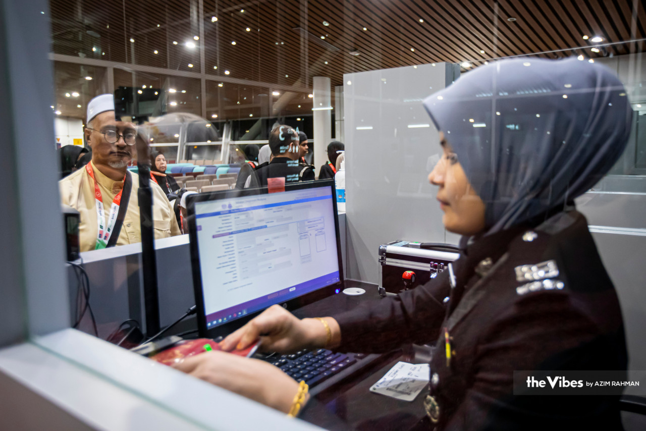 Pegawai imigresen sedang tekun memeriksa maklumat pasport milik seorang jemaah di KLIA.