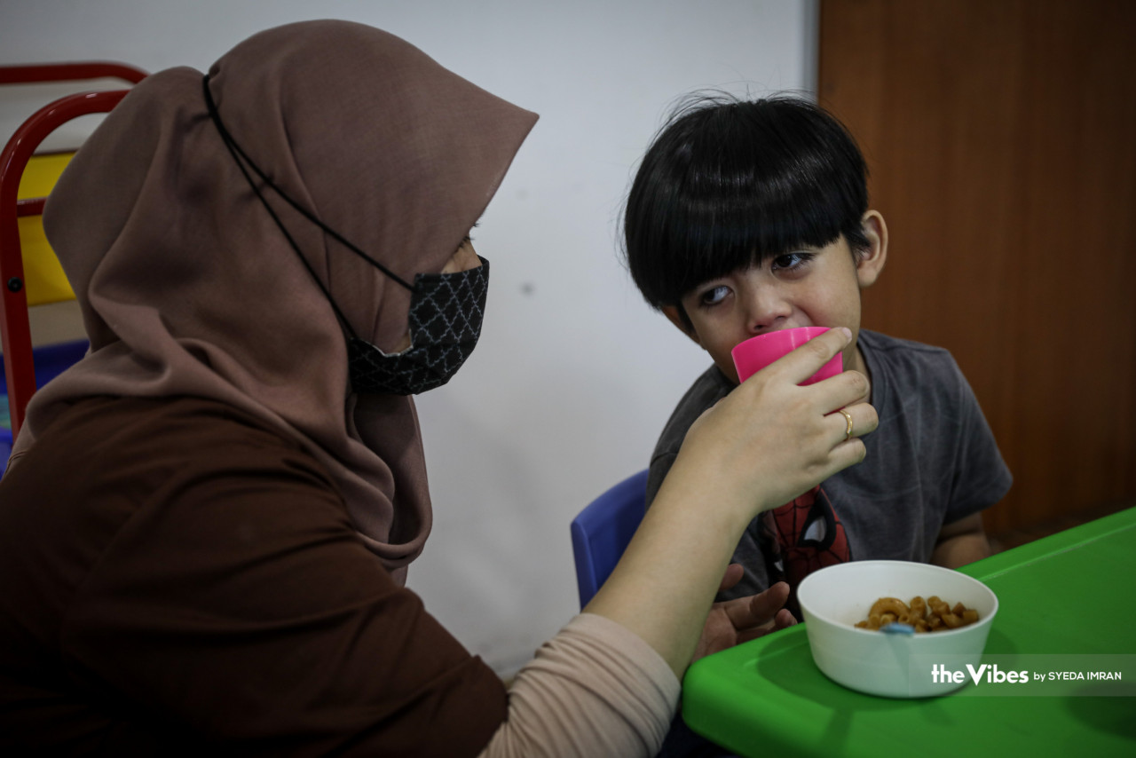 Seorang pakar terapi menyuap makanan kepada Zidan. 
