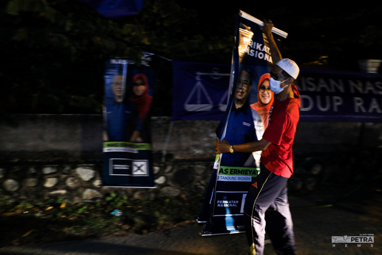 Seorang petugas jentera parti memasang sepanduk pada PRN Melaka.