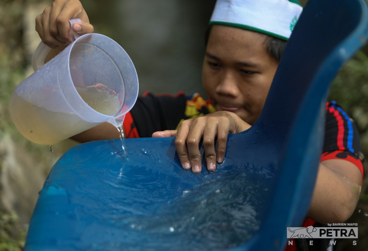 Seorang pelajar di Madrasatul Quran Darussalamah Lil Banat, membersihkan kerusi yang kotor selepas madrasah itu dinaiki air di Kampung Budiman, Meru.