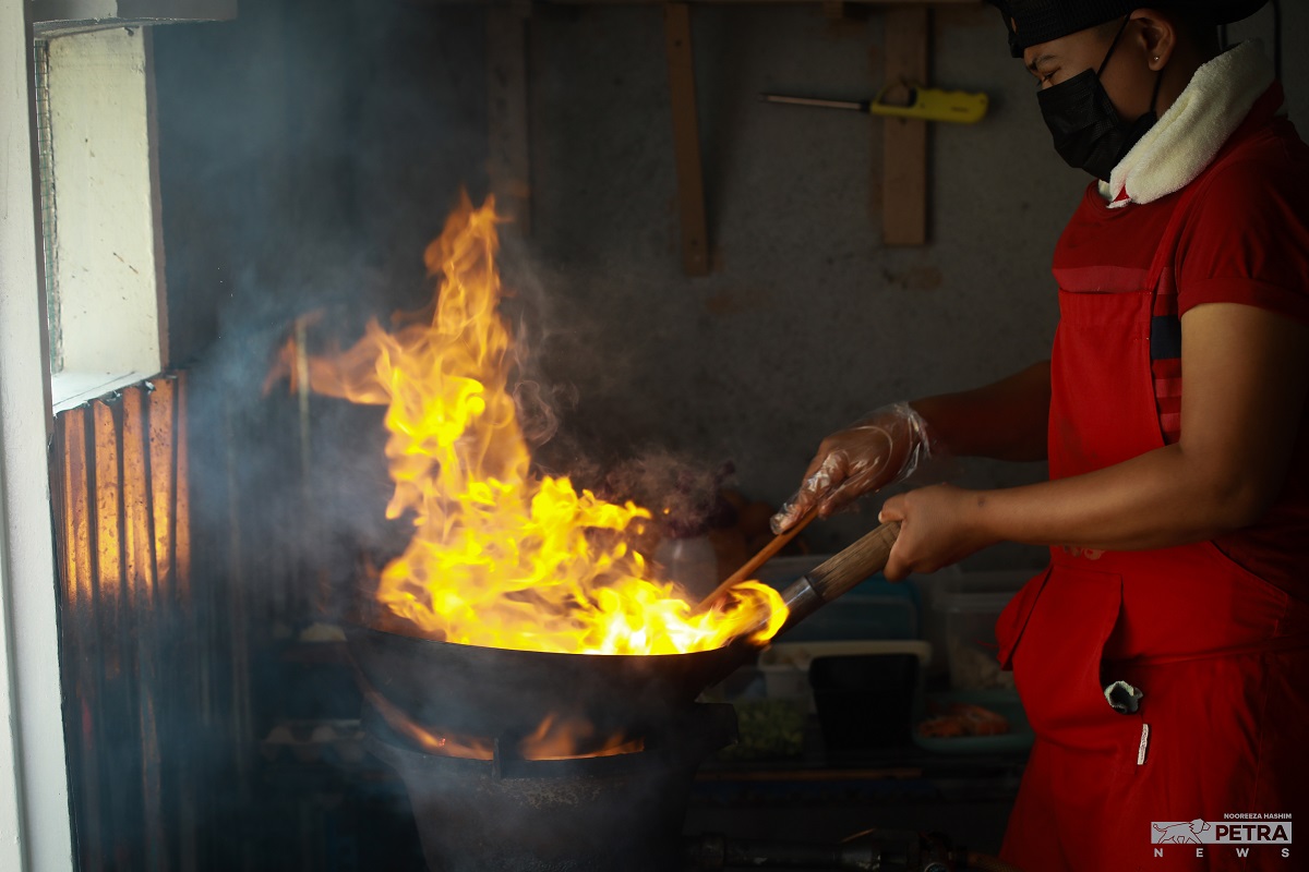 Tukang masak sedang beraksi bagi memenuhi permintaan pelanggan.
