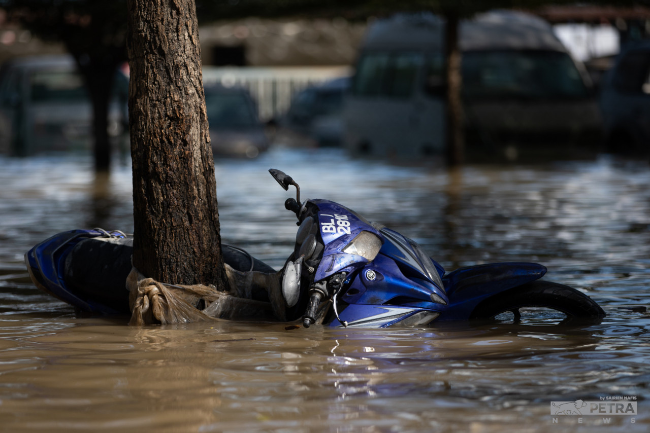 Motosikal ini ditinggalkan di tepi sebatang pokok susulan banjir, Sabtu lalu.