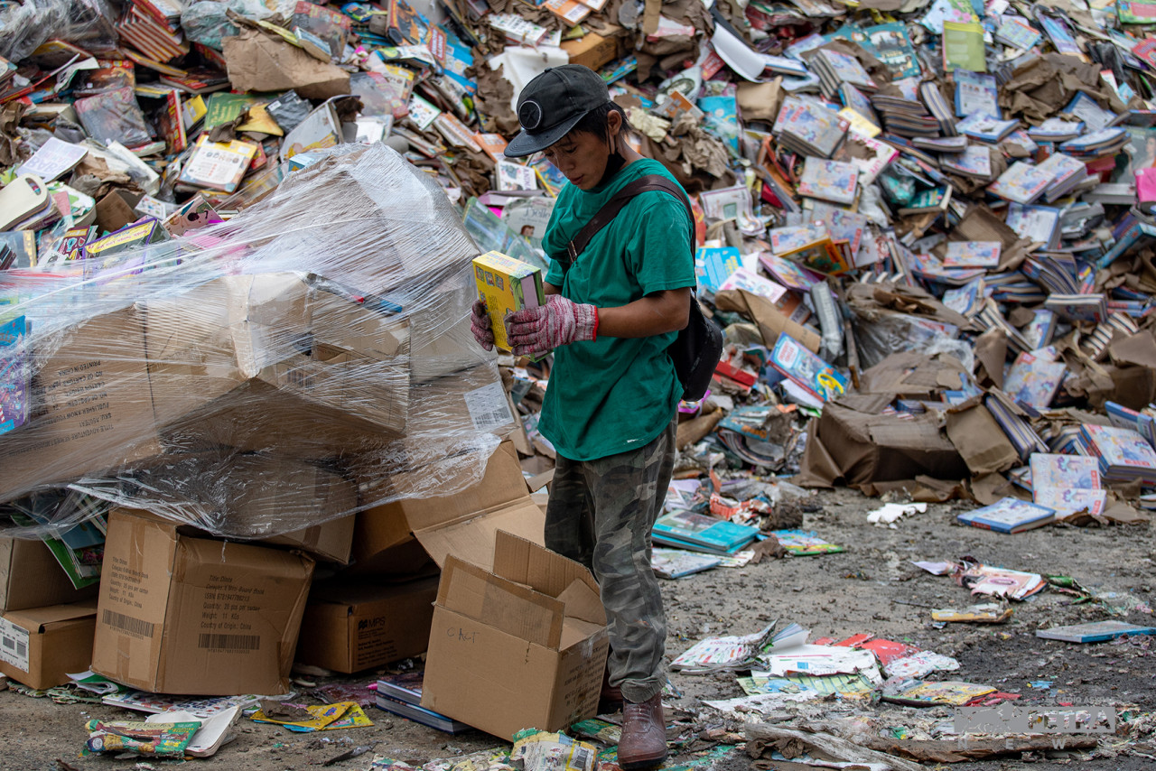 Seorang pekerja BookXcess memeriksa buku-buku yang mengalami kerosakan akibat banjir. - Gambar Sadiq Asyraf