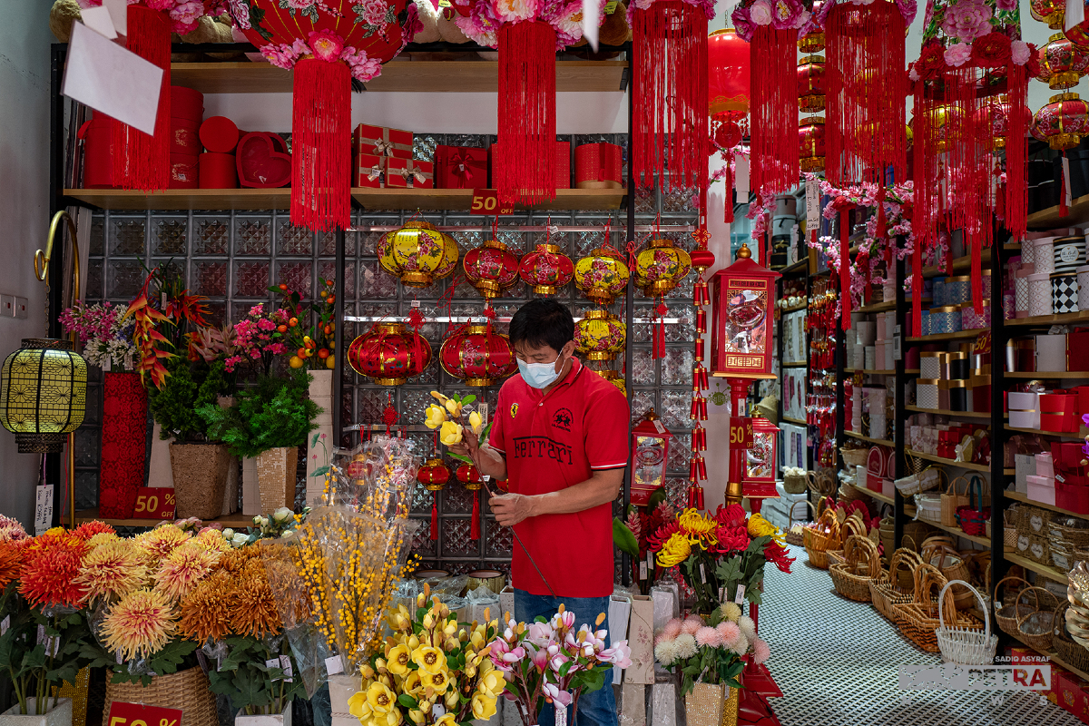 Seorang peniaga menjual barangan hiasan di Petaling Street.