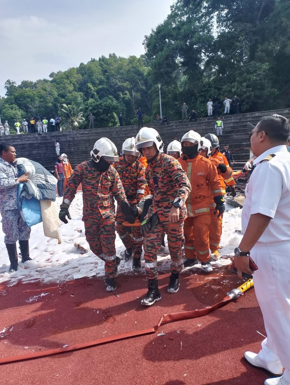 Anggota bomba dan penyelamat mengangkat seorang daripada mangsa nahas helikopter bertembung di Pangkalan TLDM Lumut. - gambar JBPM