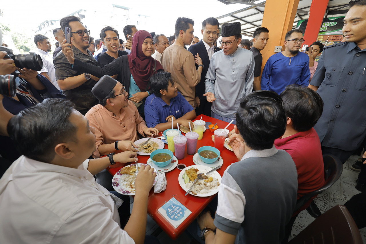 Anwar turut mencuba beberapa jenis lauk termasuk ikan bakar dan ulam-ulaman. - Gambar Bernama