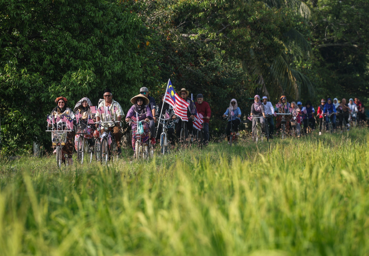 Ahmad Fauzi Ismail (tiga, kiri) bersama penduduk setempat mengayuh basikal klasik di sekitar kawasan sawah padi sempena sambutan Hari Kebangsaan Ke-66 ketika tinjauan di Butterworth hari ini. gambar BERNAMA