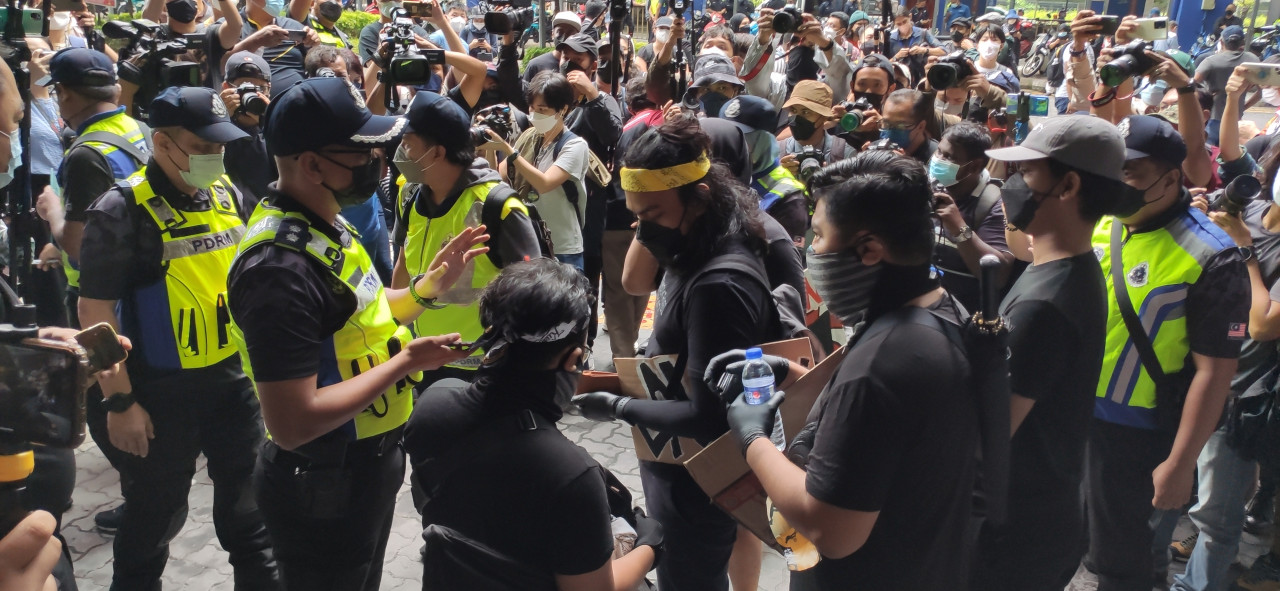 Polis menghampiri sekumpulan peserta dan memeriksa kad pengenalan mereka.