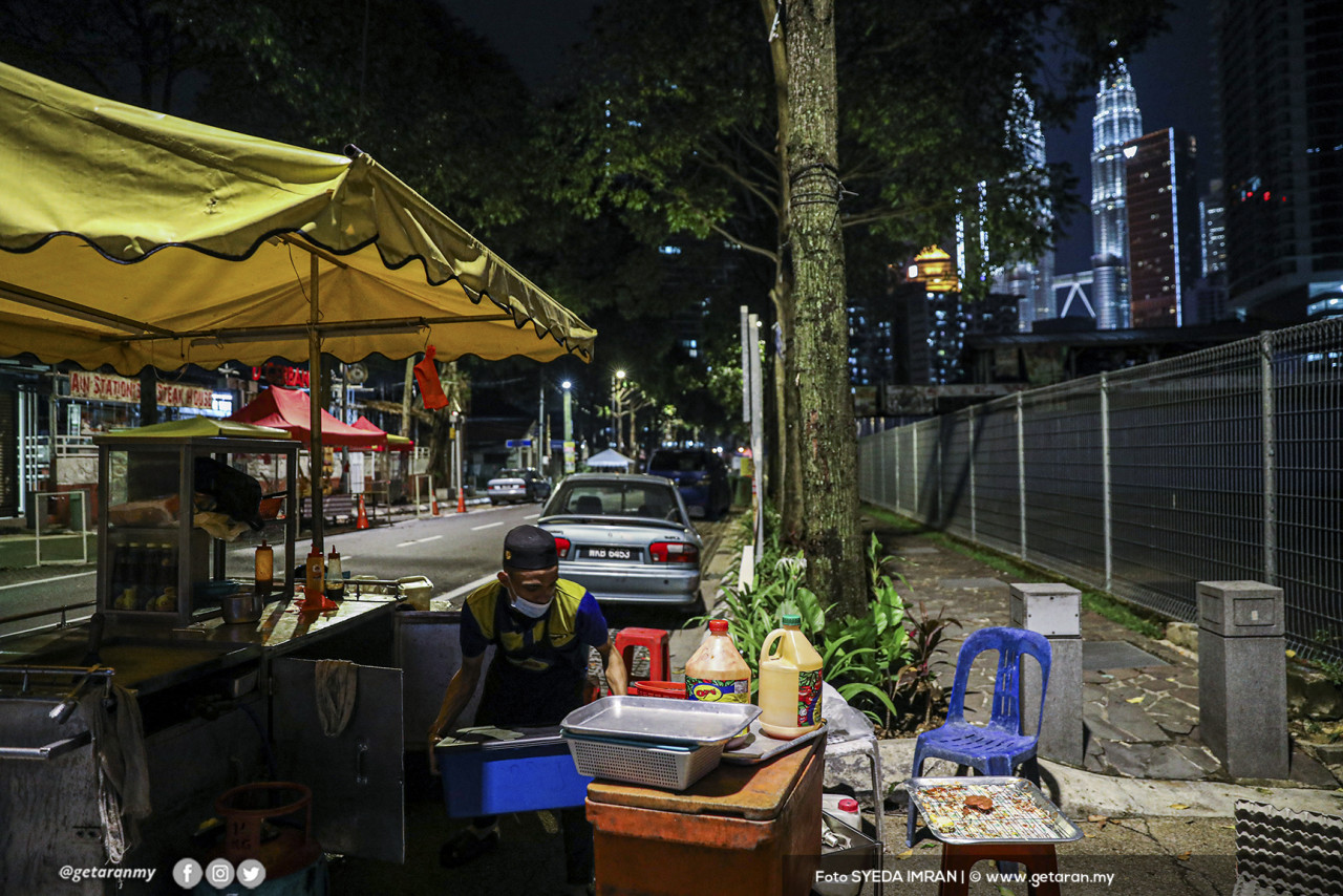 Peniaga burger ini mengemas barang jualan susulan had operasi perniagaan yang dihadkan sehingga pukul 8 malam.