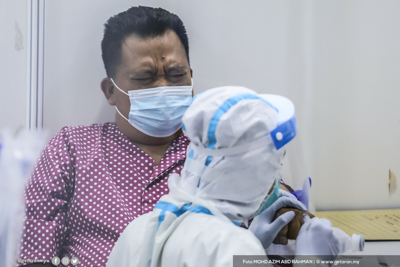 Seorang pesakit COVID-19 diberikan rawatan oleh petugas perubatan di PKRC, di MAEPS, Serdang.