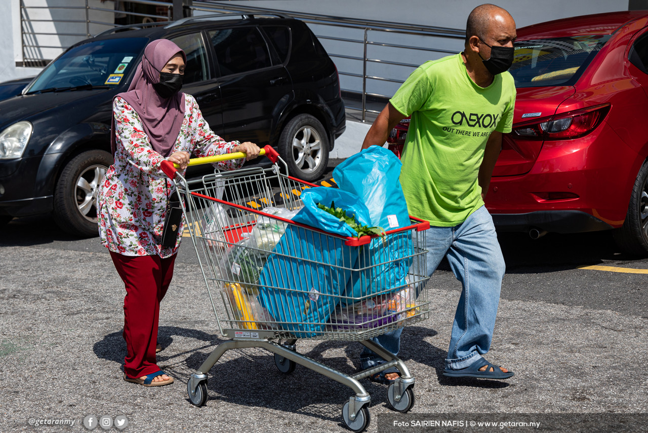Pembeli menolak troli yang dipenuhi barangan di pasar raya ST Rosham Mart di Shah Alam.