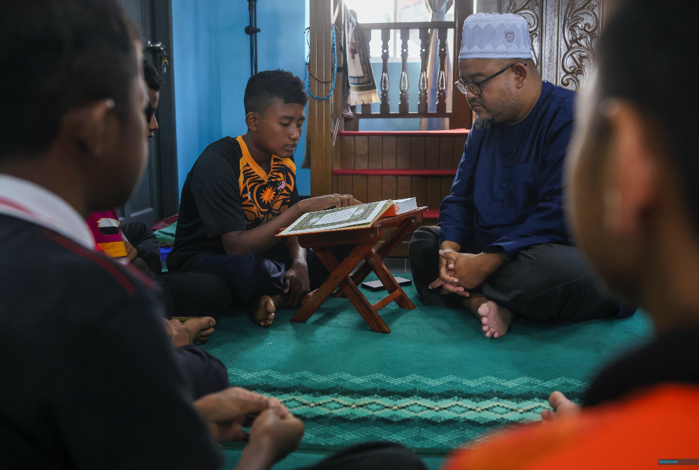 Shahrol Wizan Sulong ketika mendengar bacaan al-Quran seorang remaja Orang Asli. - gambar BERNAMA