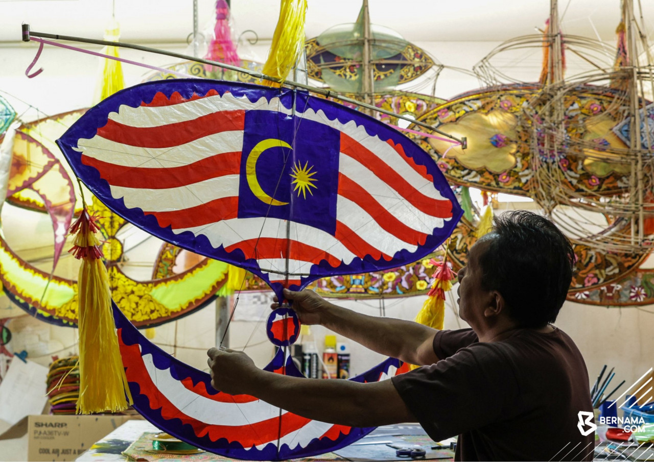 Bulan Kebangsaan menyaksikan Ahmad Kalimolleh sibuk menyiapkan wau dengan motif Jalur Gemilang. - gambar BERNAMA