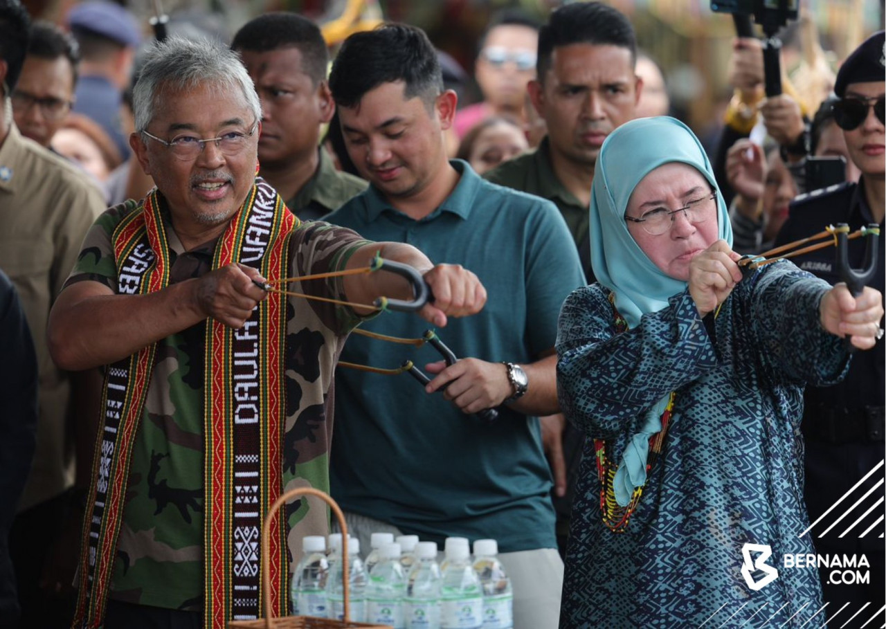 Yang di-Pertuan Agong Al-Sultan Abdullah Ri'ayatuddin Al-Mustafa Billah Shah dan Raja Permaisuri Agong Tunku Azizah Aminah Maimunah Iskandariah berkenan mencuba lastik guli ketika melawat Kompleks Persatuan Kebudayaan Kadazandusun (KDCA). - gambar BERNAMA