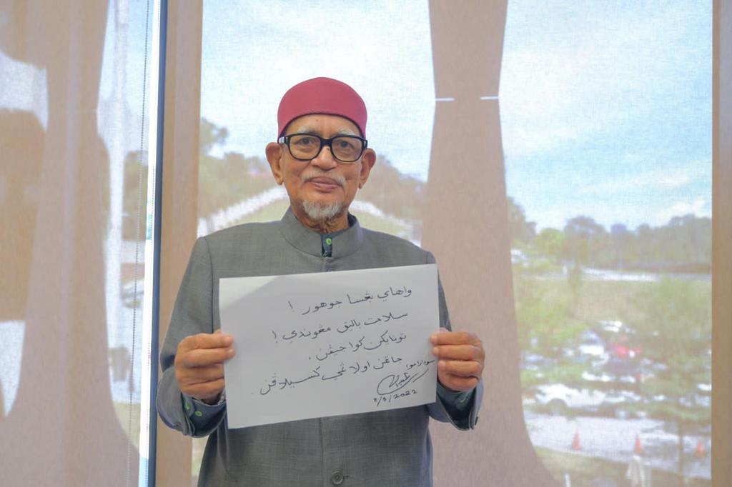 Abdul Hadi memegang plakad meminta pengundi Johor supaya melaksanakan tanggungjawab mereka esok.