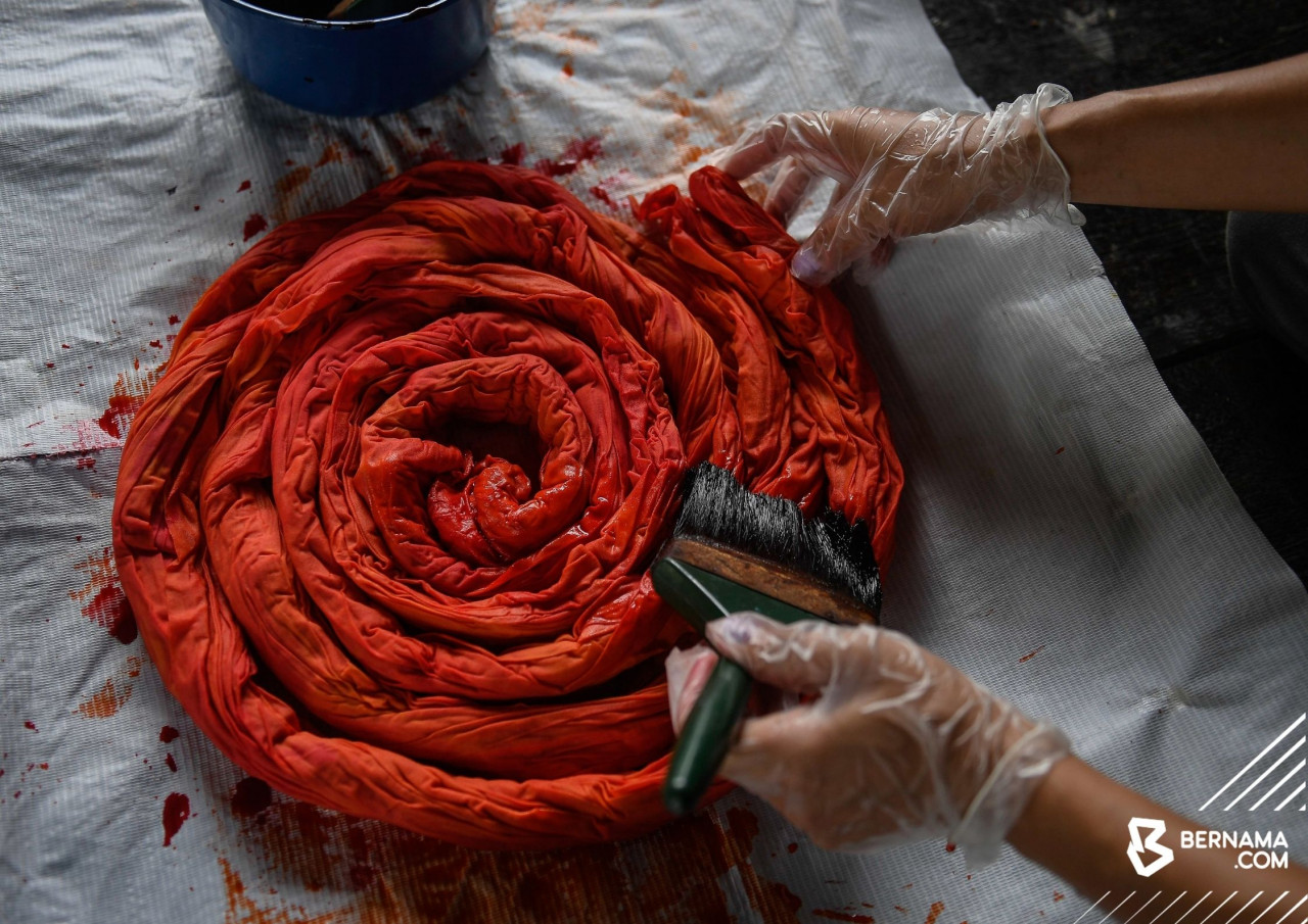 Proses mewarna batik sebelum dijemurkan di bawah pancaran matahari bagi proses pengeringan.