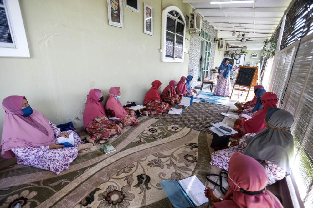 Ropia’ah mengajar rakan-rakannya bahasa Mandarin di Tasek Gelugor.