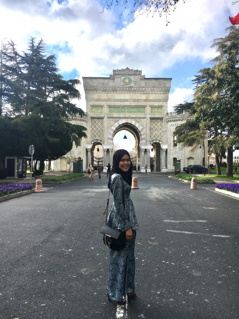 Penulis siap berbaju kurung berdiri di hadapan pintu gerbang Universiti Istanbul
