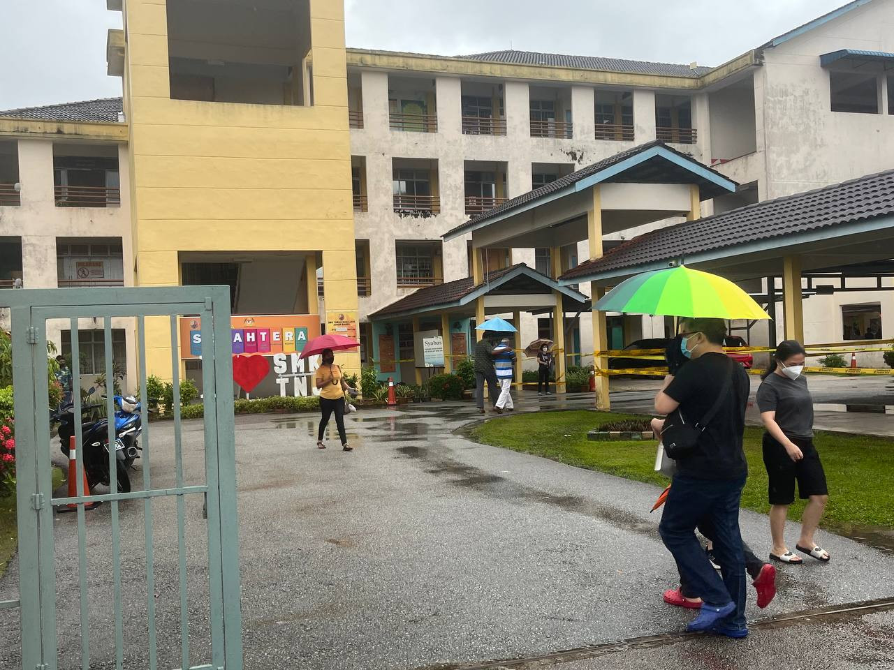 Pengundi sanggup berpayung untuk mengundi di SMK Taman Nusajaya pagi ini. - Gambar fail