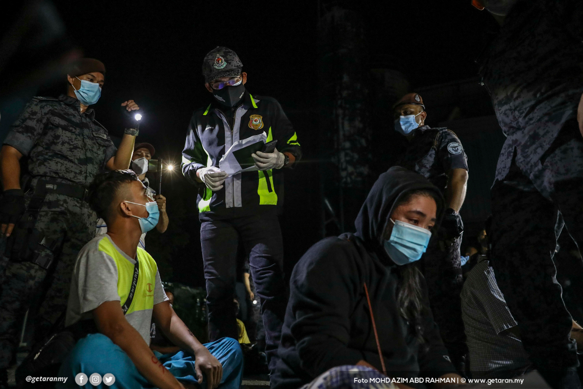 Khairul Dzaimee Daud (tengah) sedang memeriksa dokumen warga asing yang ditangkap dalam operasi di Cyberjaya, malam tadi.
