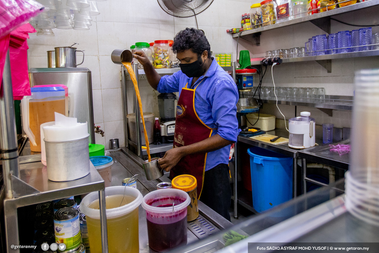 Seorang pekerja di restoran menyediakan teh tarik.