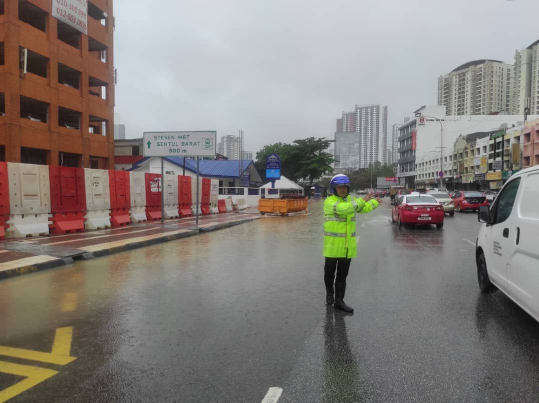 Seorang anggota polis terpaksa mengawal lalu lintas susulan banjir kilat yang melanda ibu negara hari ini. - Gambar dari PDRM