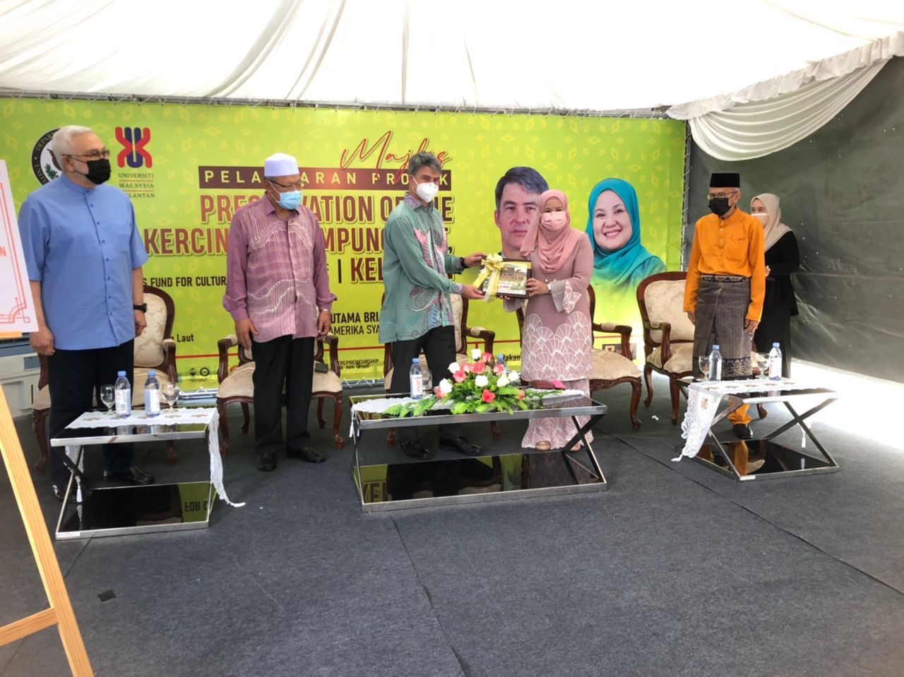 Nik Maheran (dua kanan) menyampaikan cenderahati kepada Brian pada Majlis Pelancaran Projek Pemuliharaan Rebana Kercing di Kampung Laut, Tumpat, Kelantan, hari ini.