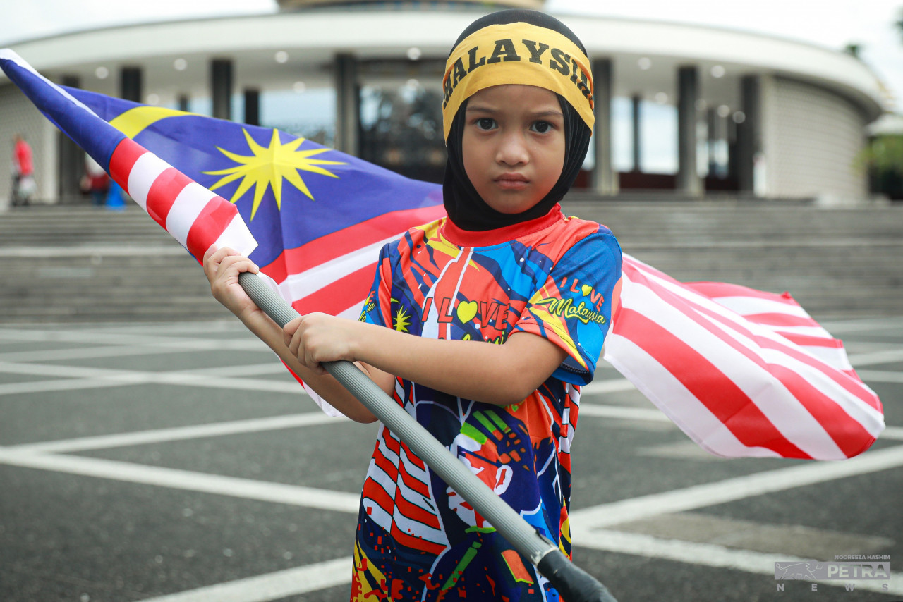 Seorang kanak-kanak mengibar Jalur Gemilang. gambar Nooreeza Hashim