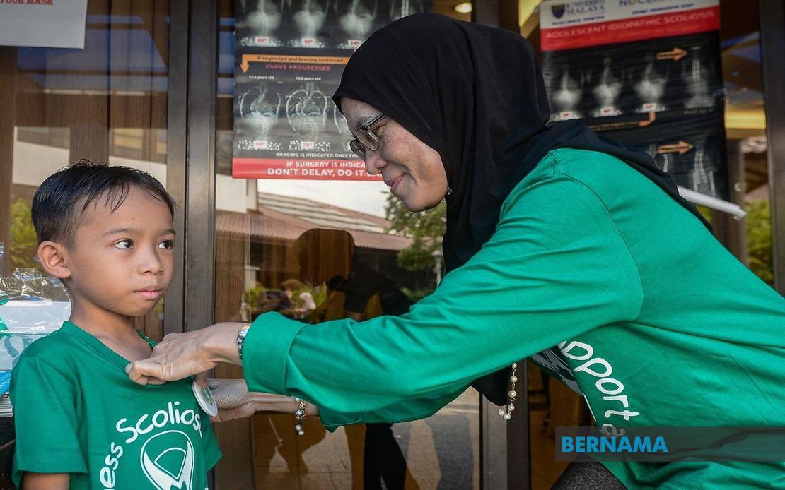 Pengerusi Kumpulan Sokongan Skoliosis Malaysia Rasidah Md Sapie (kanan) memakaikan lencana kepada peserta cilik yang hadir pada program Hari Kesedaran Skoliosis - Gambar Bernama