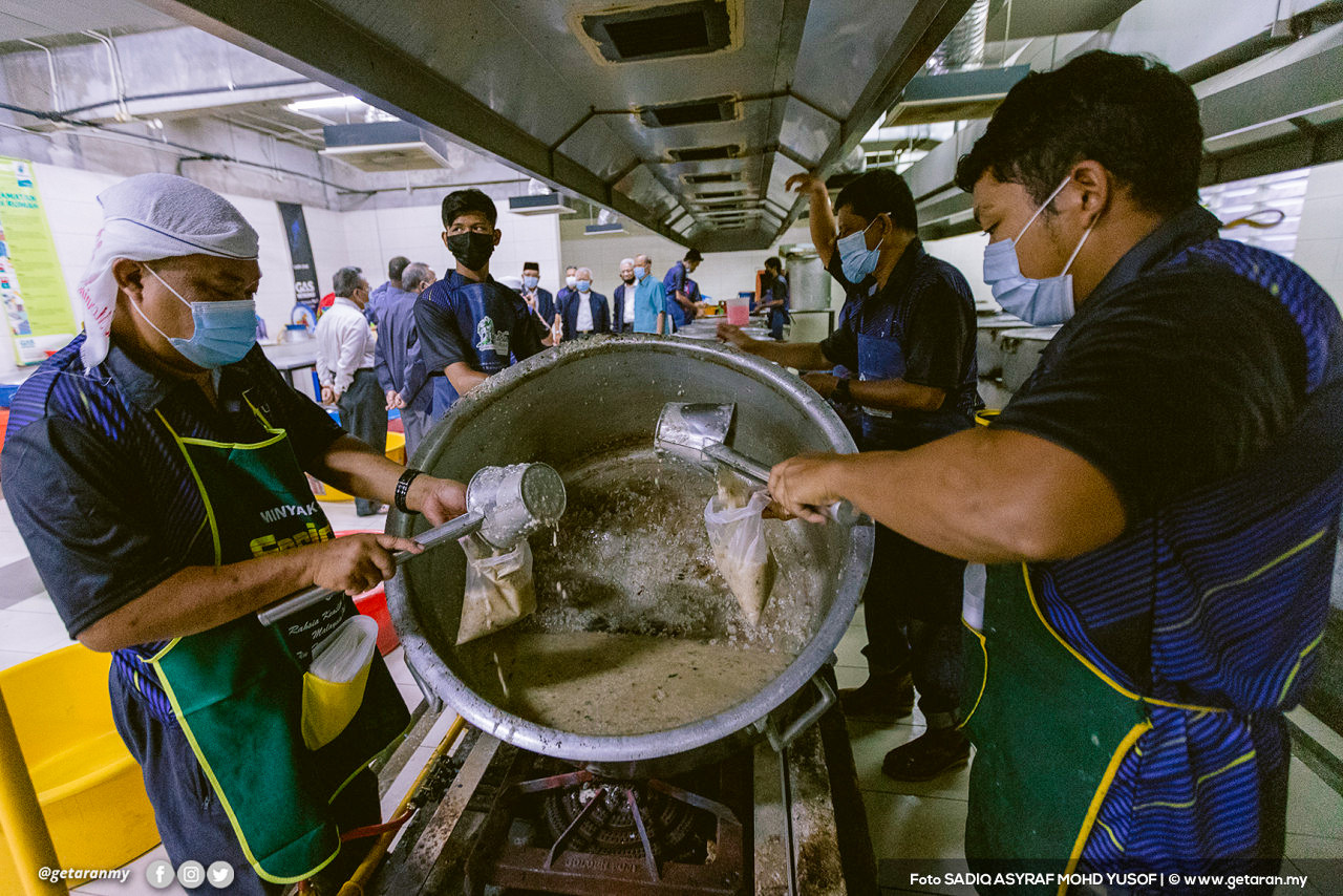 Sukarelawan memasukkan bubur lambuk kedalam pek plastik untuk diedarkan. - Gambar oleh Sadiq Asyraf