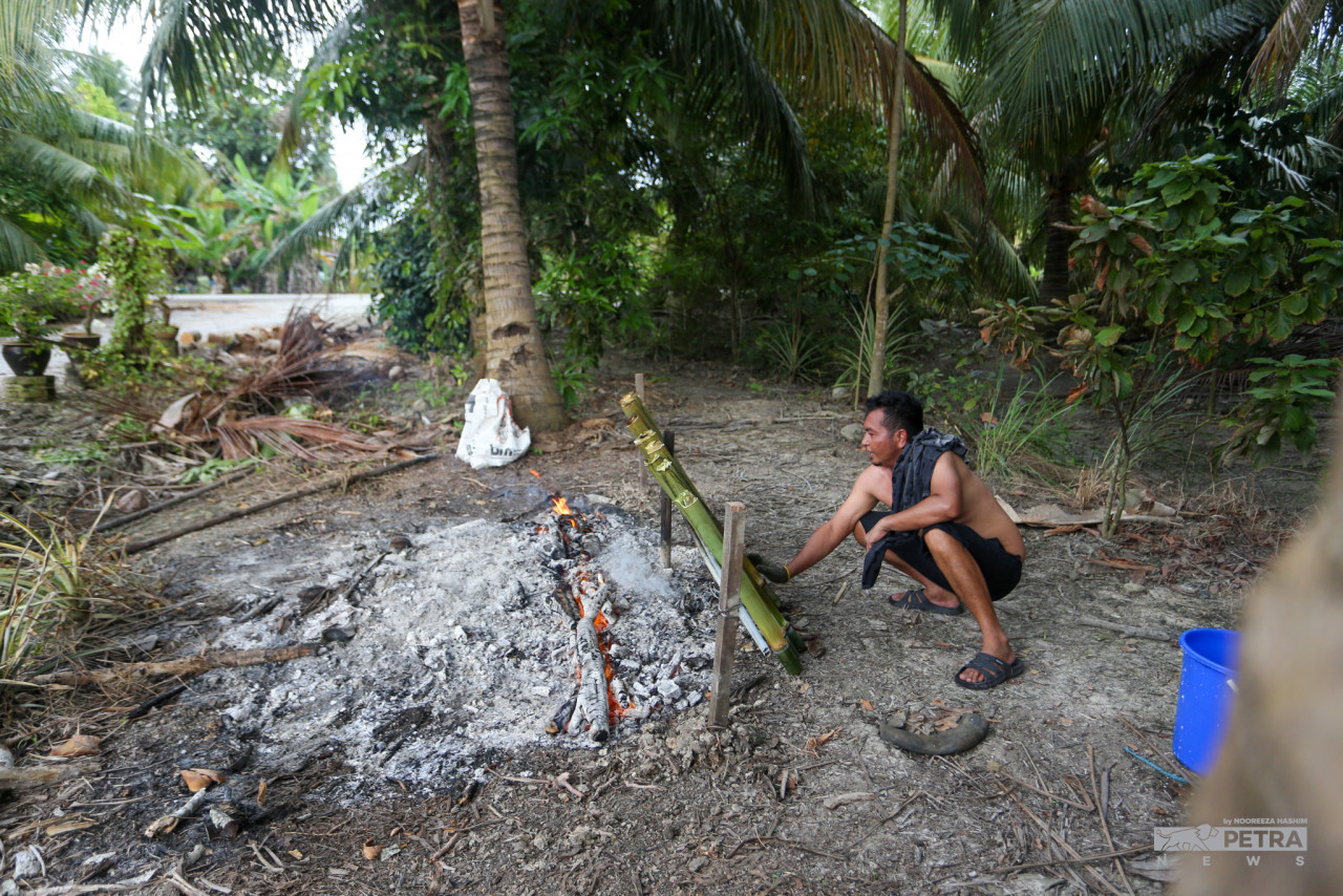 Seorang penduduk Kampung Parit Baru, Sabak Bernam, Yusuf Ahmad membakar lemang di depan rumah.