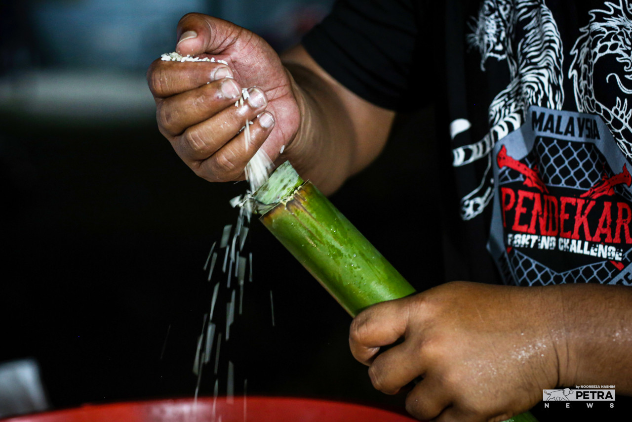 Proses awal membuat lemang dengan memasukkan beras pulut sebelum dibakar.