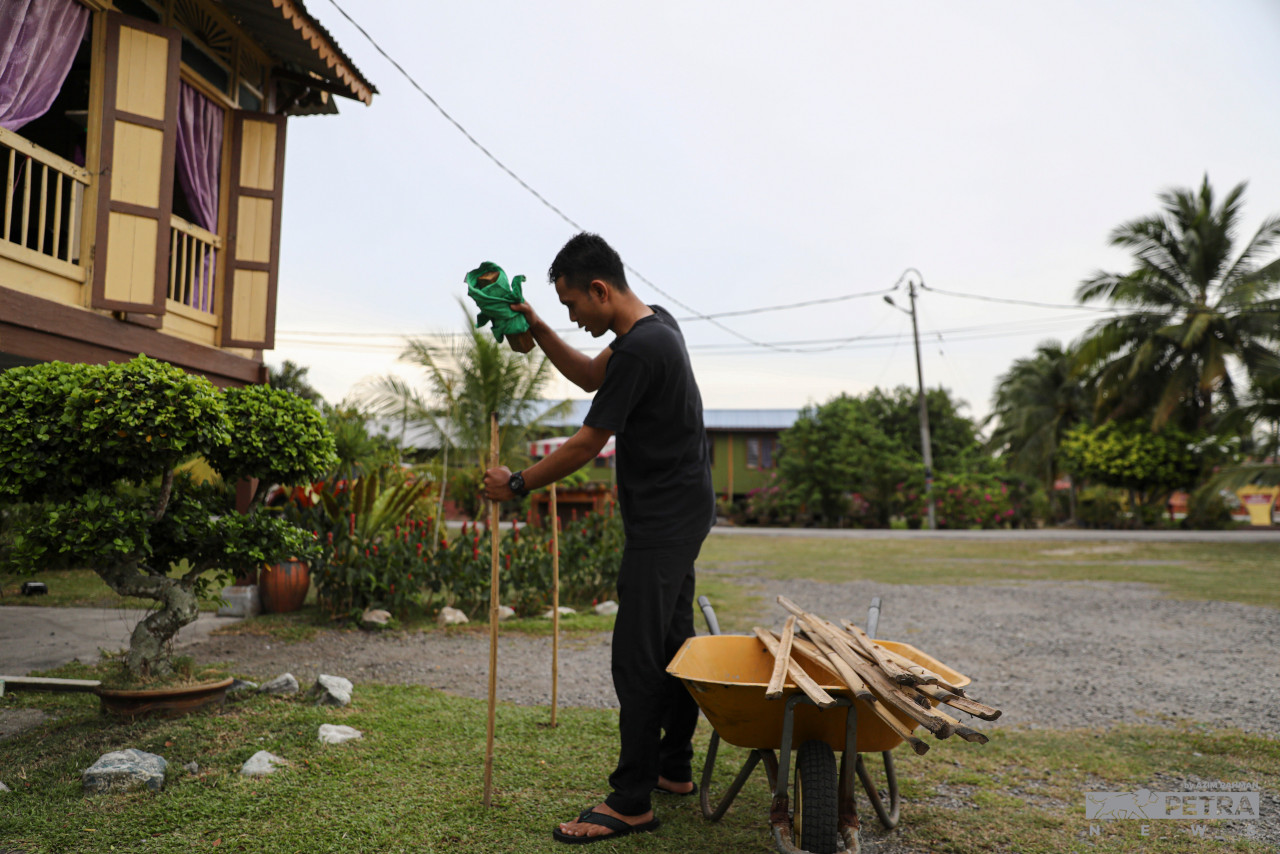 Afiq Ibtisam Tabri sibuk memasang pelita di sekitar rumah.