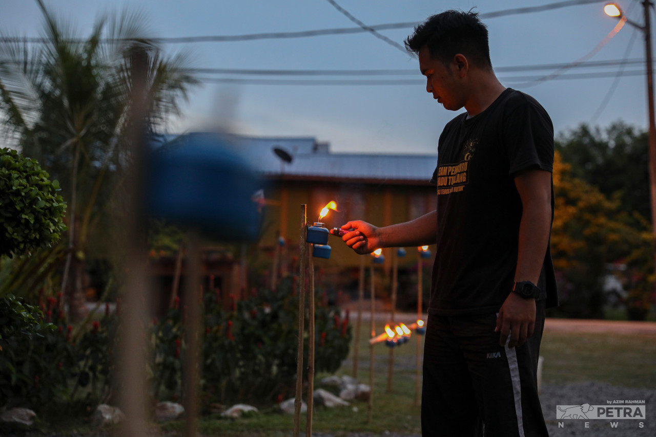 Hasydan Hisyam Tabri menyalakan pelita di sekitar rumah mereka.
