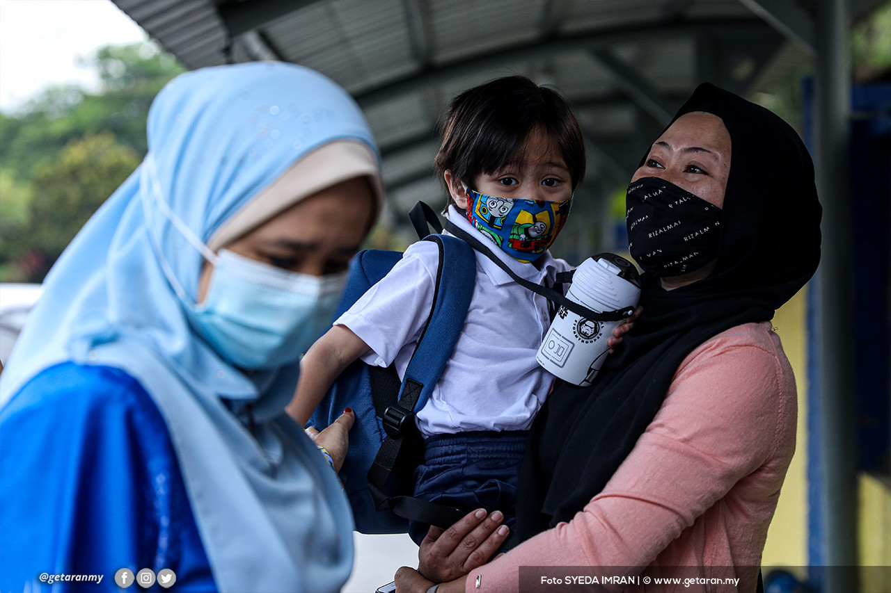Seorang murid di dokong oleh ibunya sebelum masuk ke kawasan sekolah. - Gambar Syeda Imran