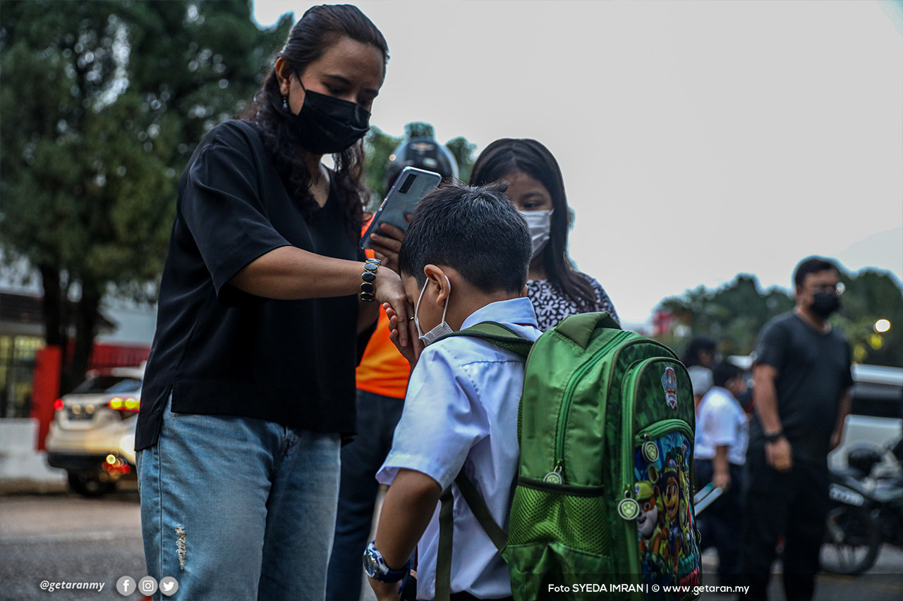 Seorang murid menyalam tangan penjaganya sebelum masuk ke kawasan sekolah. - Gambar Syeda Imran