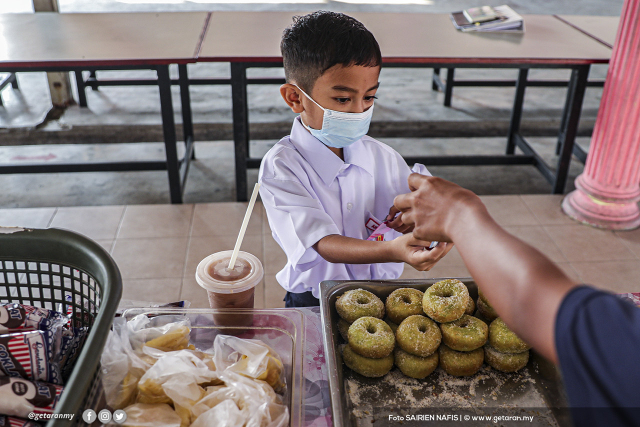Seorang murid yang memakai pelitup muka membeli makanan di kantin sekolahnya. - Gambar Sairien Nafis 