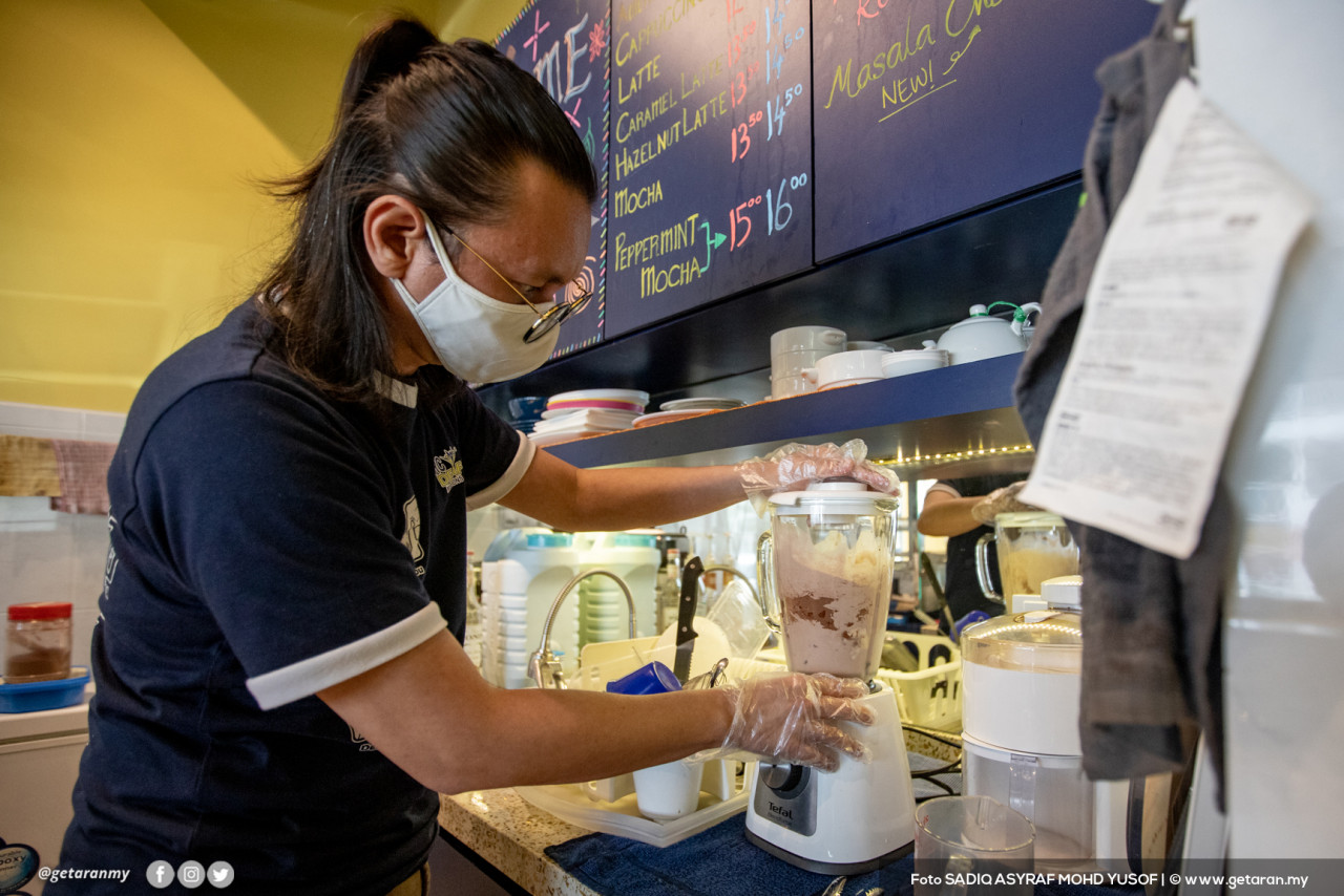 Mohammad Faizal menyediakan minuman yang dipesan pelanggan. - Gambar oleh Sadiq Asyraf