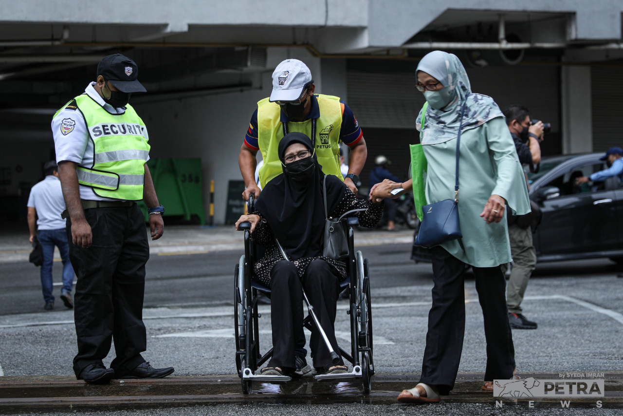 Petugas SPR sedang membantu seorang pengundi SMK Seri Pantai - Gambar oleh Syeda Imran