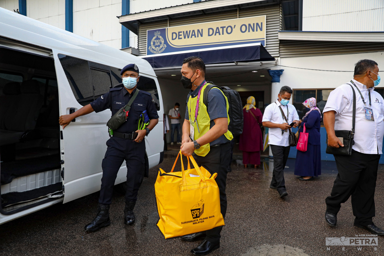 Proses membawa keluar beg berisi kertas undi bagi pengundian awal dikawal ketat anggota polis. - Gambar Azim Abd Rahman