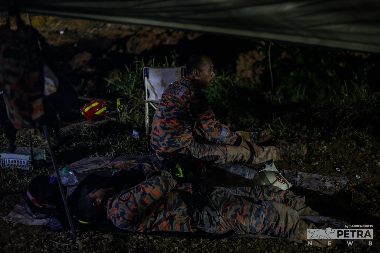 Anggota bomba yang kepenatan menjalankan usaha mencari mangsa, berehat sebentar. - Gambar oleh Sairien Nafis