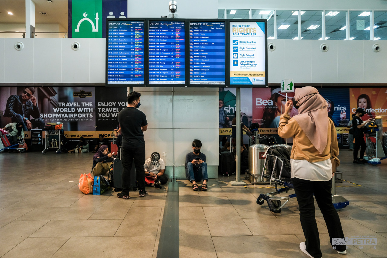 Orang ramai melihat paparan informasi yang menunjukkan kelewatan jadual penerbangan di KLIA2. - Gambar oleh Abdul Razak Latif