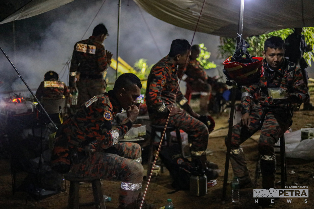 Anggota bomba yang terlibat dalam usaha mencari mangsa kejadian tanah runtuh, berehat untuk makan malam semalam. - Gambar oleh Sairien Nafis
