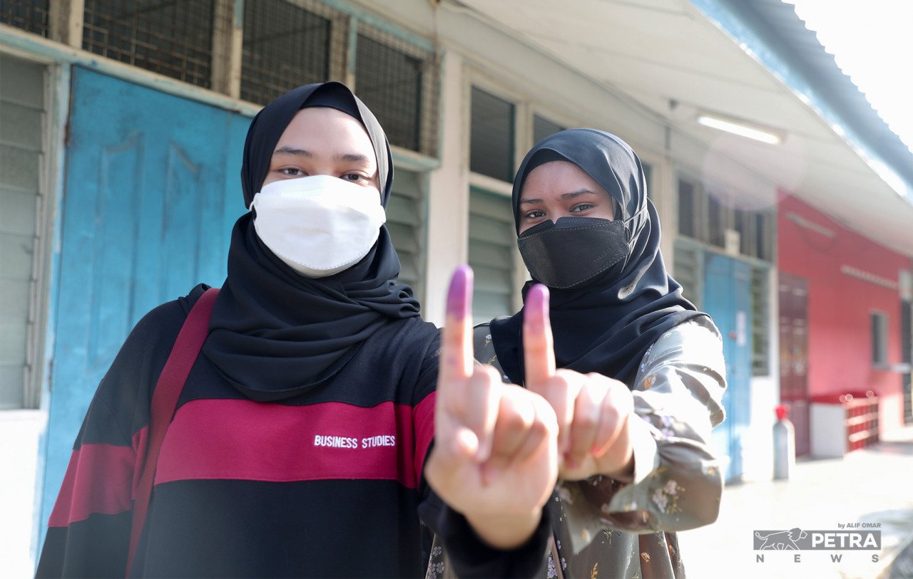 Atiqah Salehuddin (kanan), 24, dan adiknya Athirah (21) membuang undi di SMK Aminuddin Baki Perling sempena PRN Johor. 