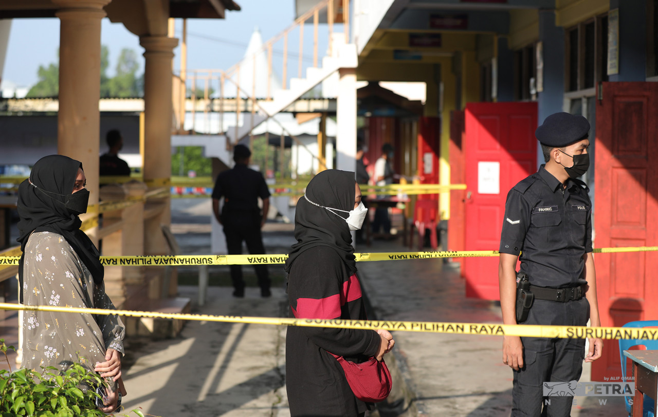 Atiqah (kiri) dan Atirah berbaris sebelum dibenarkan masuk ke bilik mengundi. 