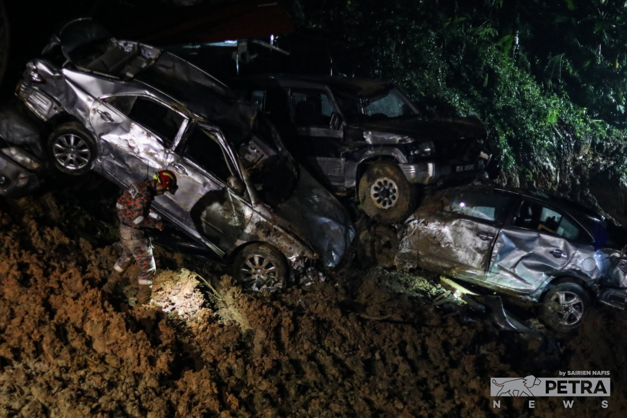 Seorang anggota bomba memeriksa timbunan kereta yang musnah akibat kejadian tanah runtuh di Batang Kali. - Gambar oleh Sairien Nafis