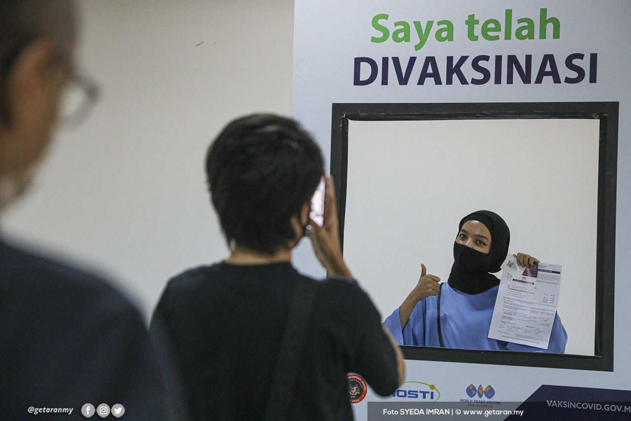 Seorang wanita mengambil kesempatan untuk gambarnya diambil selepas menerima vaksin AstraZeneca. - Gambar oleh Syeda Imran